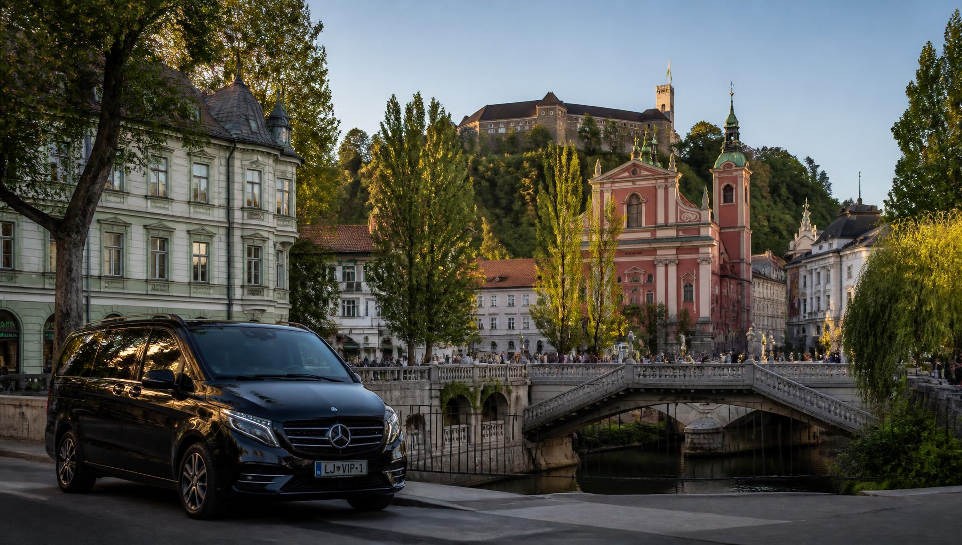 Črn Mercedes V class ob Tromostovju v Ljubljani z Ljubljanskim gradom, Slovenija